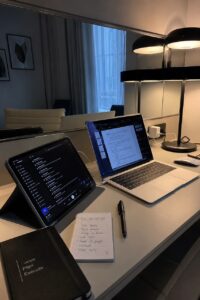 A laptop, tablet, and planner arranged on a desk in a modern digital marketing workspace.