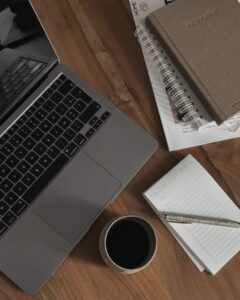 A laptop, notebook, and coffee on a desk representing a digital marketing workspace.